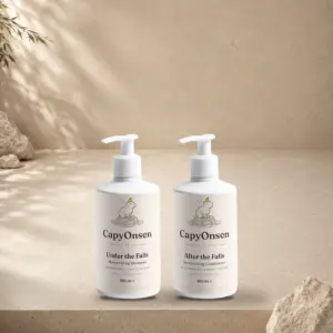CapyOnsen Hair Ritual Set: Moisturising Shampoo (290ml) and Moisturising Conditioner (290ml) pump bottles standing side by side on a sunlit stone surface