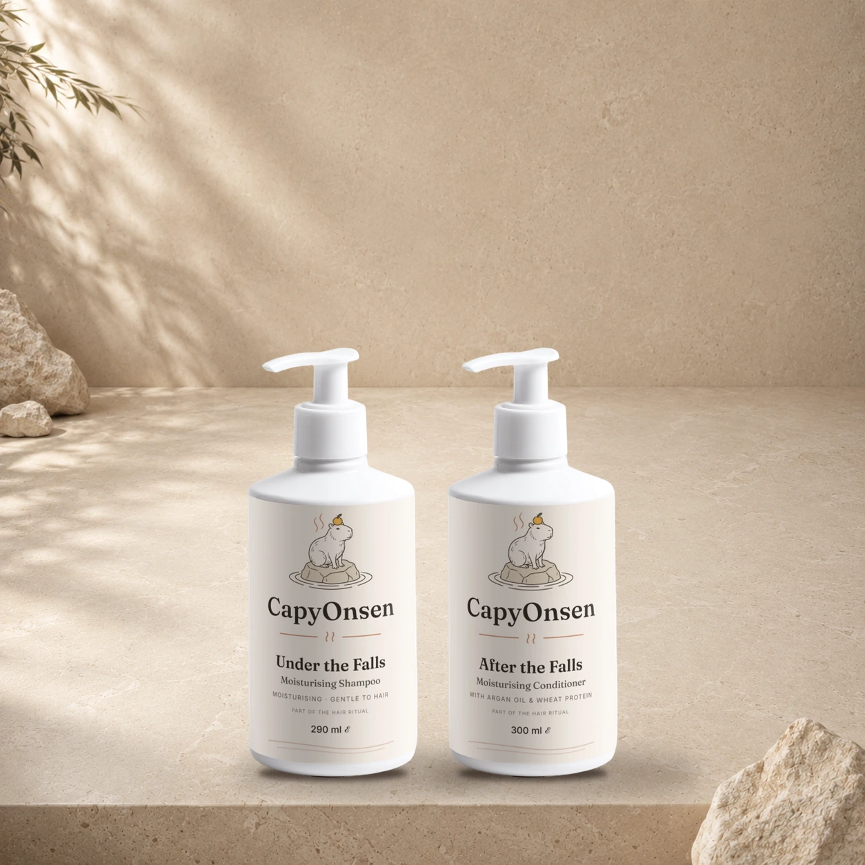 CapyOnsen Hair Ritual Set: Moisturising Shampoo (290ml) and Moisturising Conditioner (290ml) pump bottles standing side by side on a sunlit stone surface